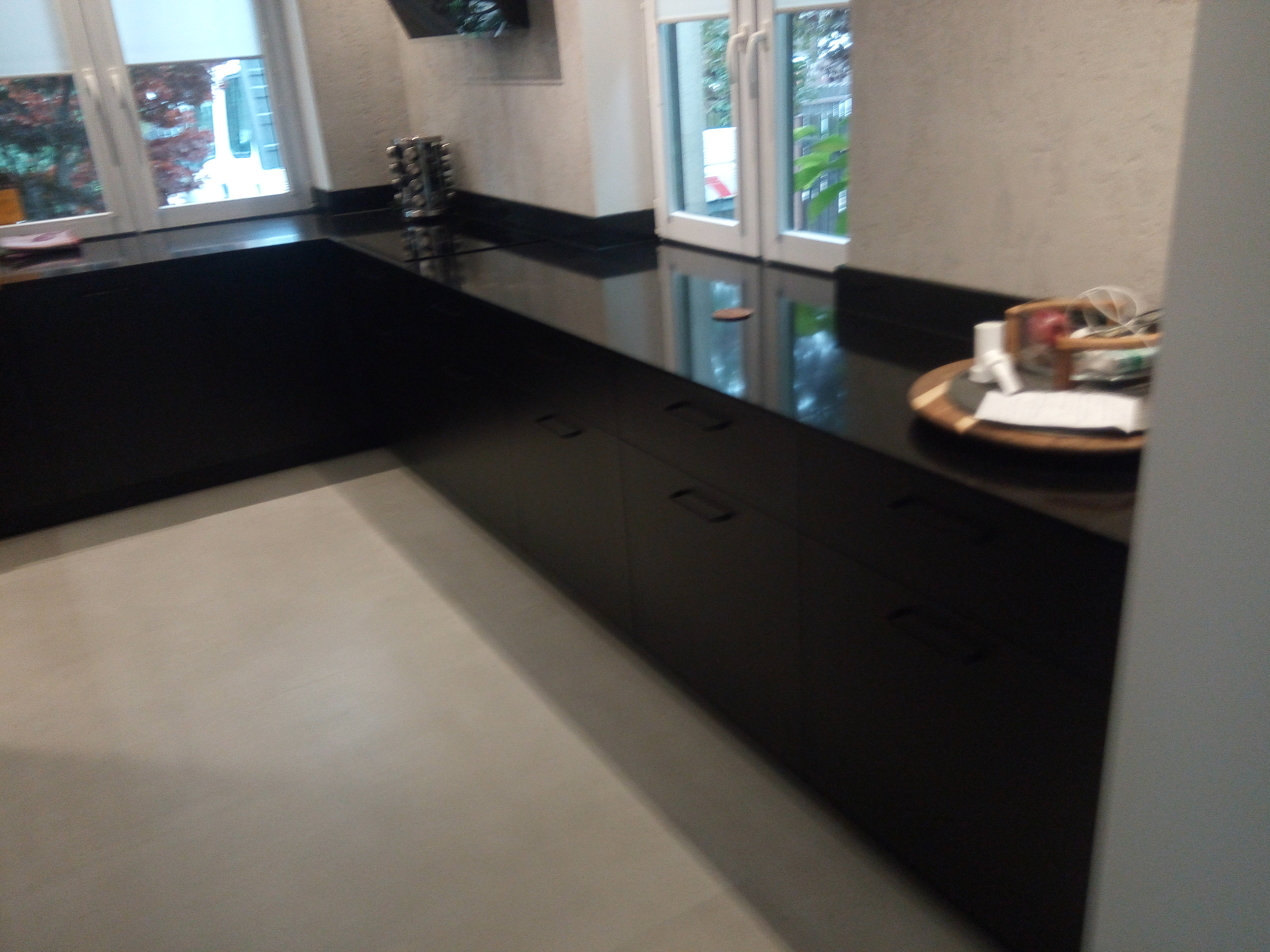 Ciemna kuchnia z długim blatem i zabudową pod oknami