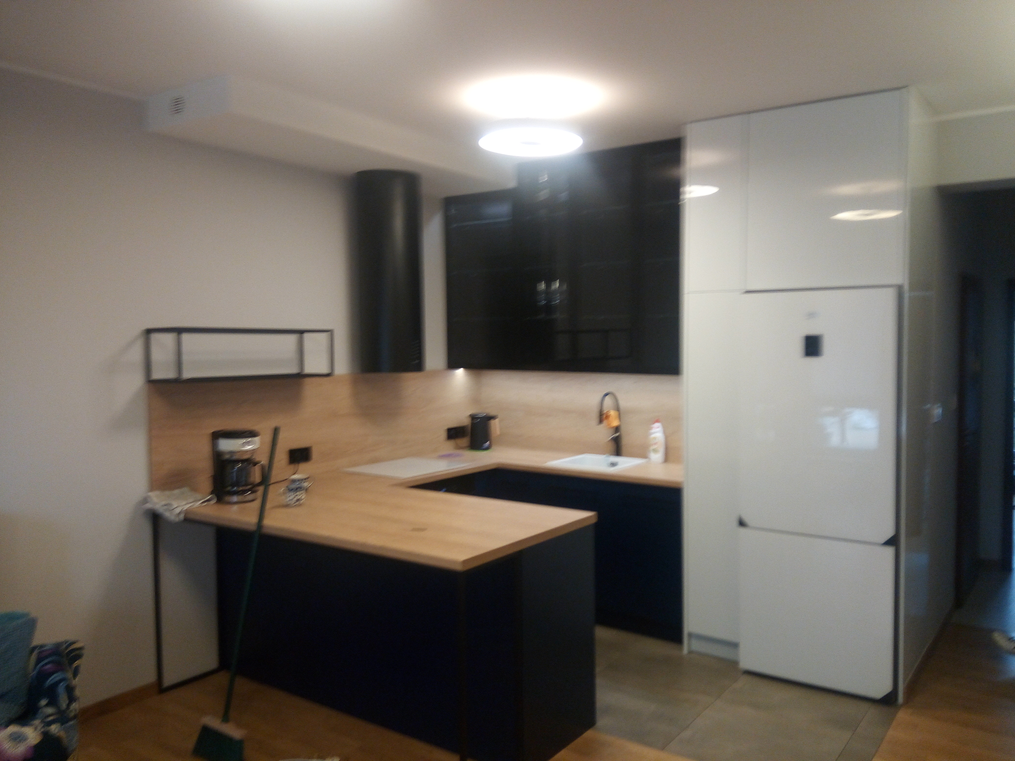 Kuchnia z drewnianym blatem, czarnymi i białymi frontami