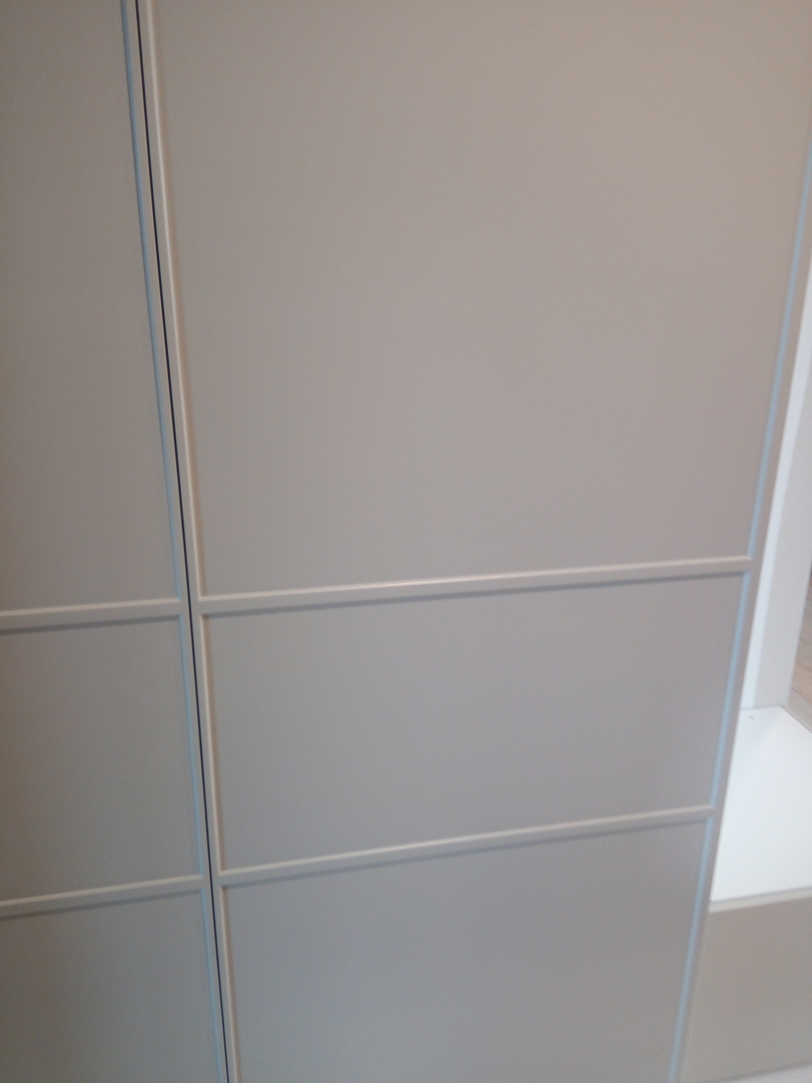 Detal beżowej szafy z frezowanymi podziałami