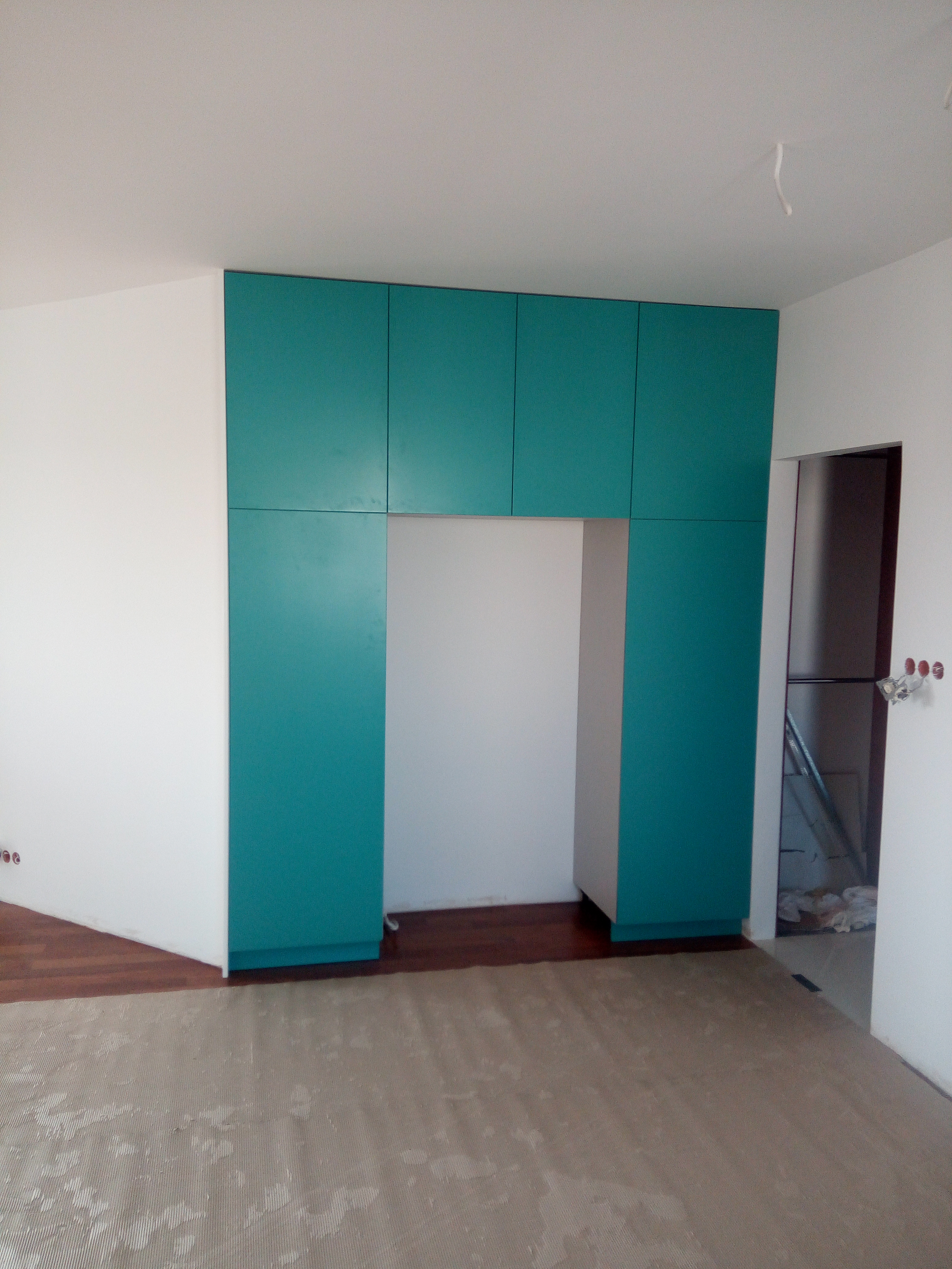 Turkusowa zabudowa szaf wokół wnęki